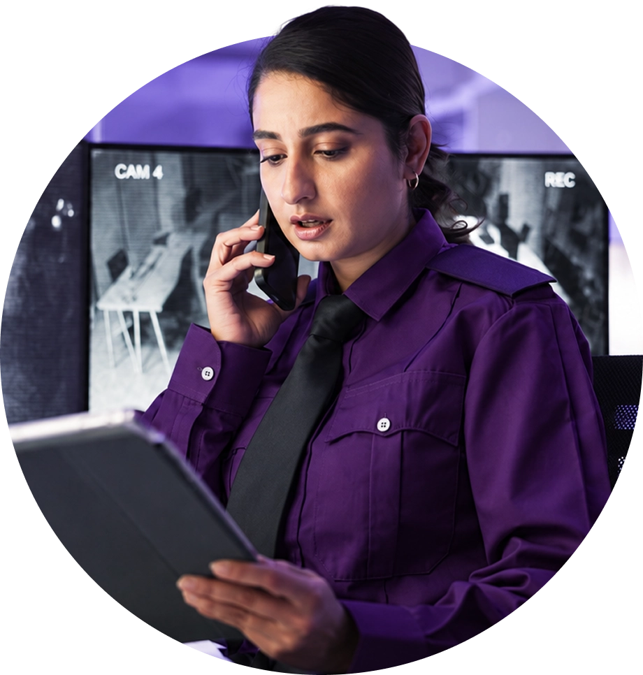 Profissional da portaria ao telefone, consultando o tablet na central de monitoramento